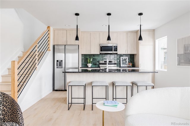 kitchen featuring appliances with stainless steel finishes, an island with sink, and decorative light fixtures