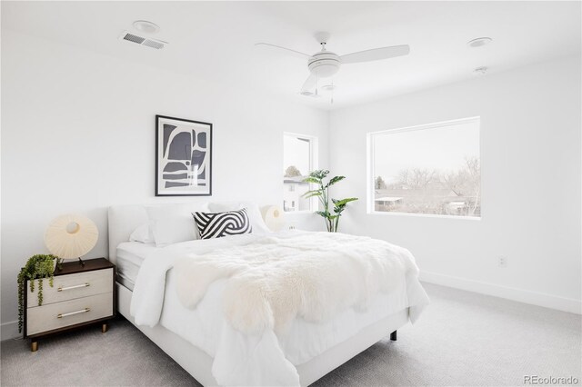 carpeted bedroom featuring a ceiling fan, visible vents, and baseboards