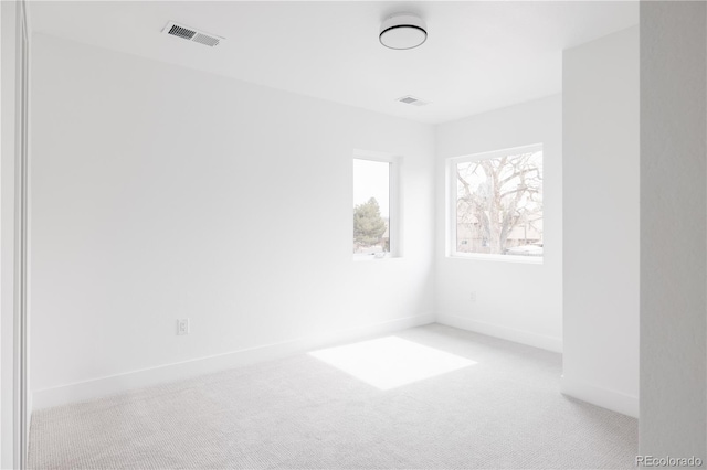 spare room featuring baseboards, visible vents, and light colored carpet