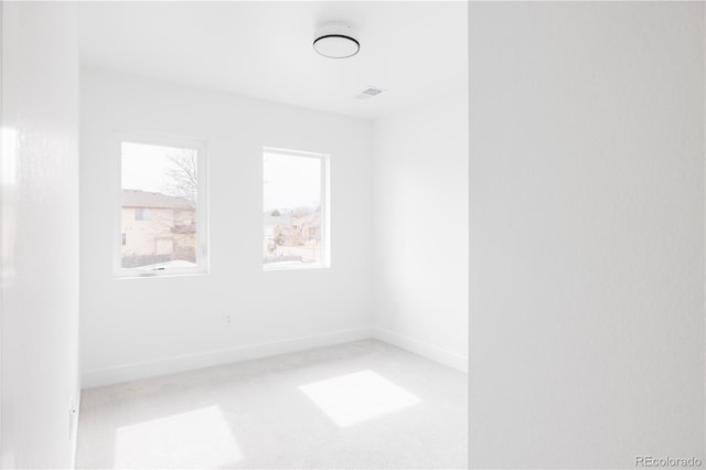 unfurnished room featuring visible vents, baseboards, and light colored carpet