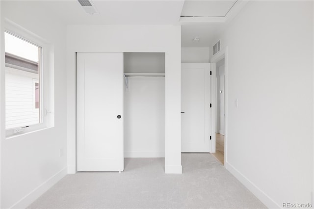 unfurnished bedroom with a closet, visible vents, light carpet, and baseboards