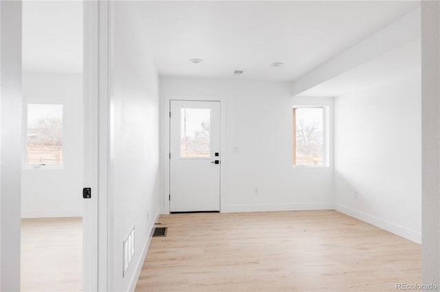 doorway with baseboards, visible vents, and light wood-style floors