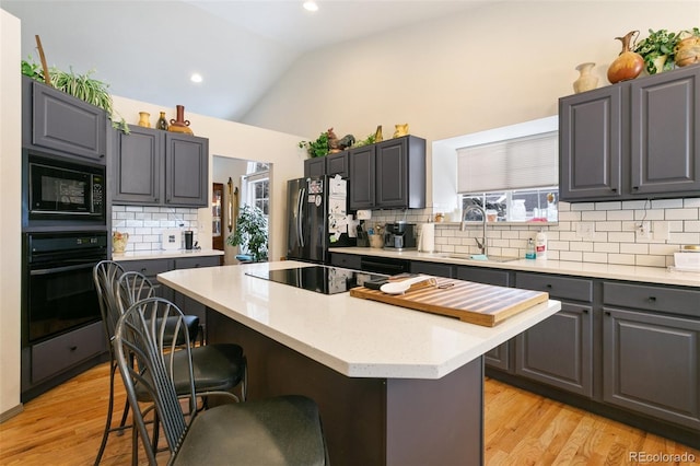 kitchen featuring a kitchen island, sink, gray cabinetry, and black appliances