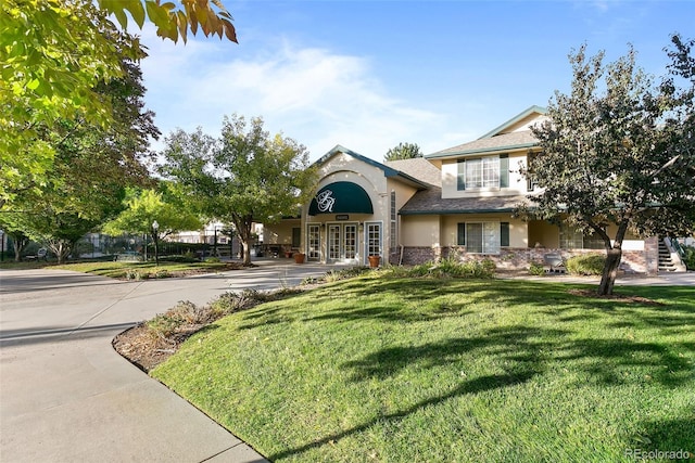 view of front of home with a front lawn, french doors, and stucco siding