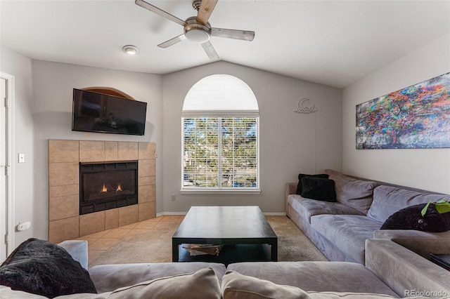 carpeted living room featuring baseboards, a ceiling fan, a tiled fireplace, and vaulted ceiling