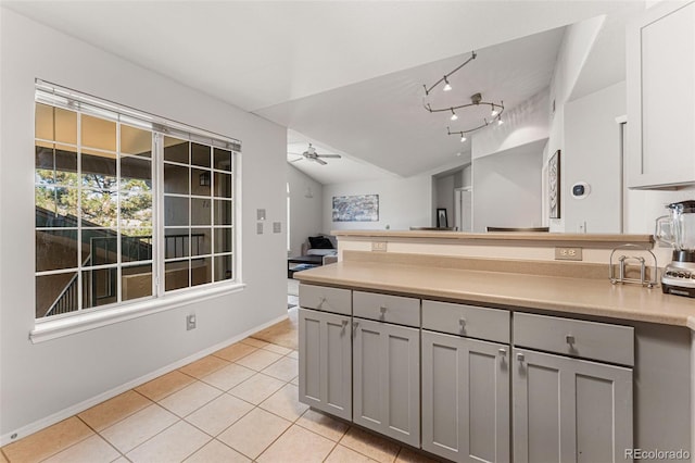 kitchen featuring gray cabinetry, a ceiling fan, a peninsula, light tile patterned flooring, and lofted ceiling