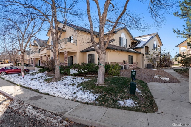 multi unit property with a balcony, stucco siding, and central AC