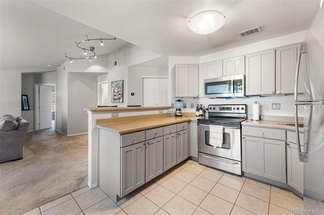 kitchen featuring visible vents, gray cabinets, open floor plan, appliances with stainless steel finishes, and a peninsula