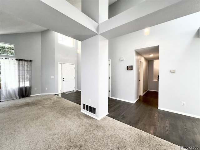 carpeted empty room featuring a towering ceiling and a wealth of natural light