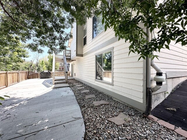 view of side of property featuring fence, a wooden deck, and stairs