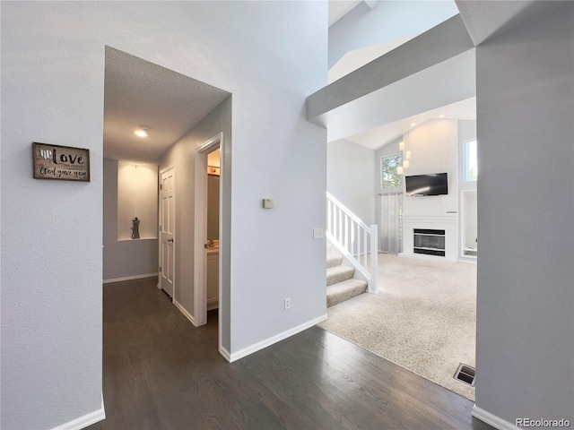 corridor with visible vents, carpet flooring, wood finished floors, baseboards, and stairs