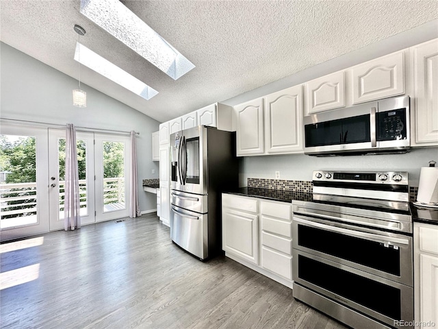 kitchen featuring appliances with stainless steel finishes, dark countertops, light wood-style flooring, and white cabinetry