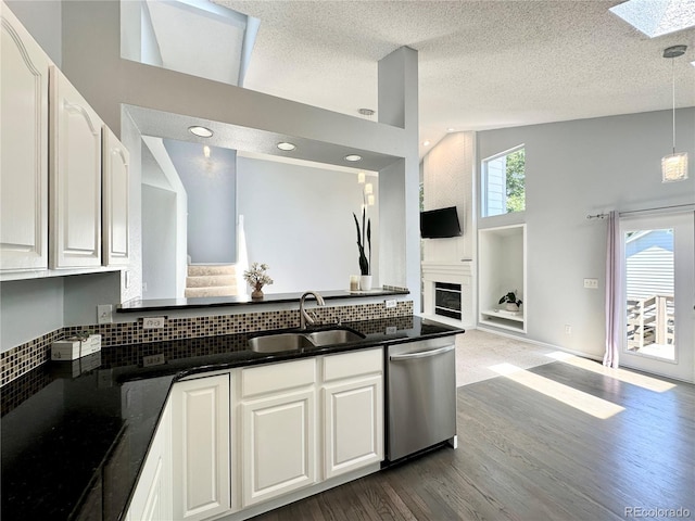 kitchen featuring dark wood-style floors, a fireplace, stainless steel dishwasher, open floor plan, and a sink