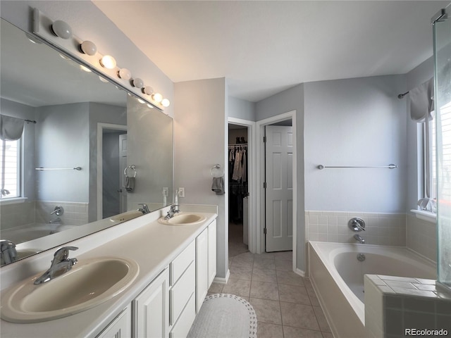 bathroom with a garden tub, double vanity, tile patterned flooring, and a sink