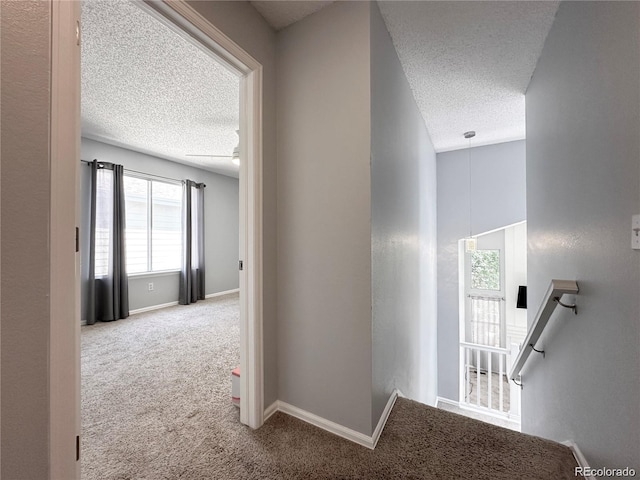 hall featuring carpet flooring, a textured ceiling, and baseboards