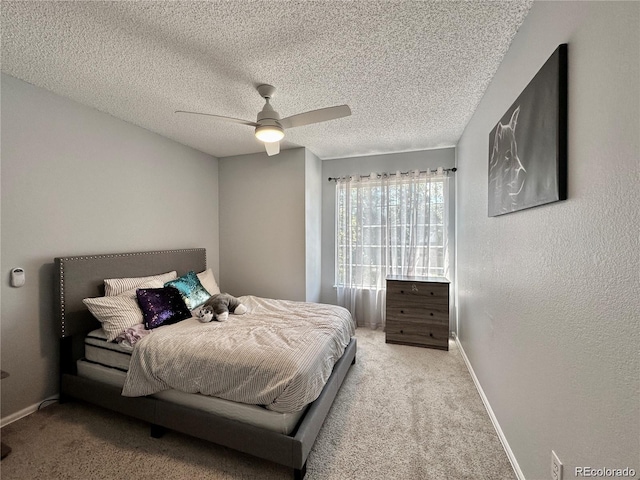 bedroom featuring a textured ceiling, a textured wall, carpet flooring, a ceiling fan, and baseboards