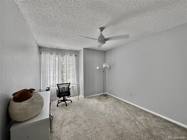 unfurnished office with a textured ceiling, a textured wall, carpet flooring, a ceiling fan, and baseboards