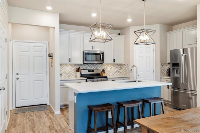 8586 Holman Ct Unit A, Arvada, CO 80005 - kitchen with stainless steel appliances, a sink, a kitchen breakfast bar, light countertops, and a center island with sink