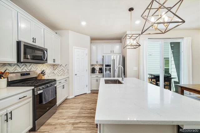 8586 Holman Ct Unit A, Arvada, CO 80005 - kitchen featuring appliances with stainless steel finishes, a chandelier, a kitchen island with sink, a sink, and decorative backsplash