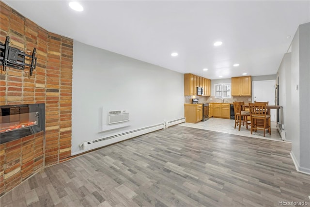 living room with light hardwood / wood-style flooring, sink, a baseboard heating unit, a fireplace, and a wall mounted AC