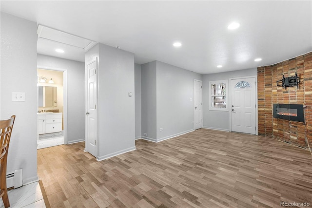 2190 S Holly St Unit 207, Denver, CO 80222 - unfurnished living room with light hardwood / wood-style floors, a large fireplace, and a baseboard heating unit