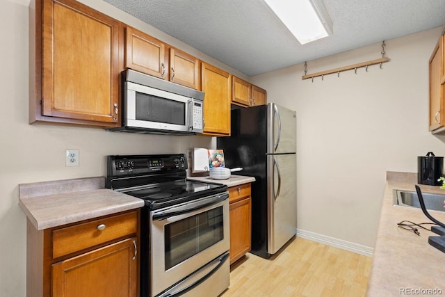 10212 W 80th Dr Unit C, Arvada, CO 80005 - kitchen with appliances with stainless steel finishes, light wood-style flooring, light countertops, and brown cabinets