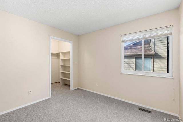 10212 W 80th Dr Unit C, Arvada, CO 80005 - unfurnished bedroom with carpet, a walk in closet, a textured ceiling, and a closet
