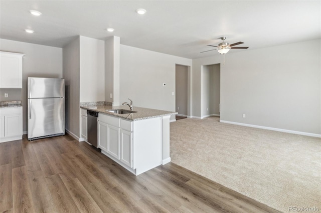 2164 Alyssa St, Fort Lupton, CO 80621 - kitchen with appliances with stainless steel finishes, a peninsula, white cabinets, light stone countertops, and ceiling fan