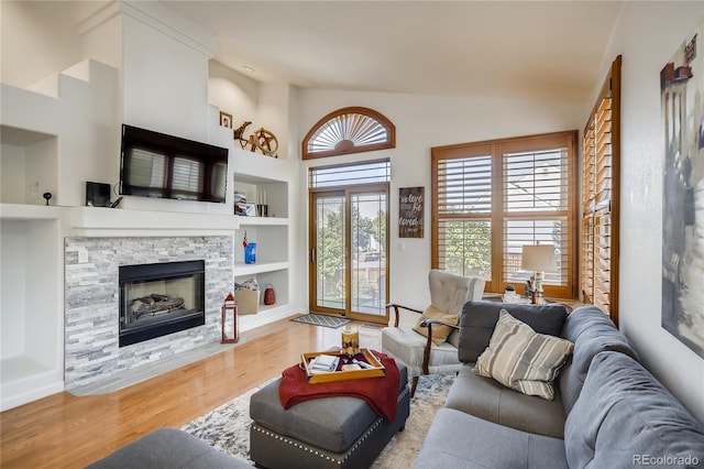 9451 Desert Willow Trl, Highlands Ranch, CO 80129 - living room with wood finished floors, built in shelves, a stone fireplace, and high vaulted ceiling