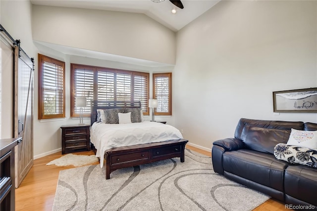 9451 Desert Willow Trl, Highlands Ranch, CO 80129 - bedroom with a barn door, baseboards, light wood finished floors, and high vaulted ceiling