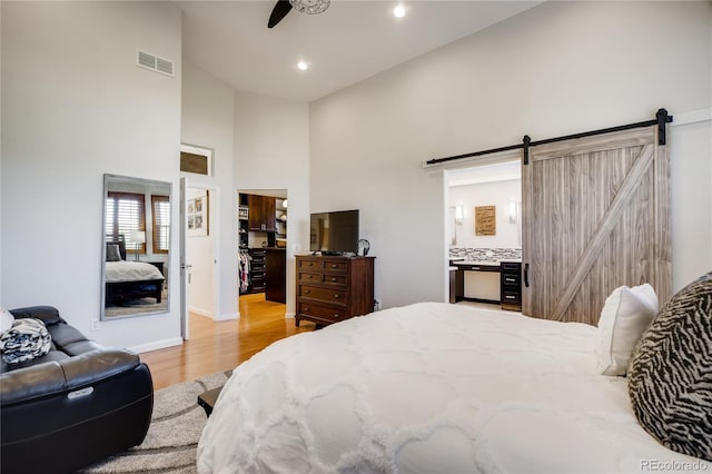 9451 Desert Willow Trl, Highlands Ranch, CO 80129 - bedroom with a barn door, light wood-style floors, high vaulted ceiling, recessed lighting, and baseboards