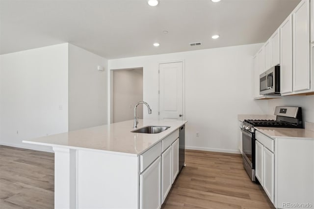 9672 Cathay St, Commerce City, CO 80022 - kitchen featuring a sink, light wood-style floors, baseboards, a kitchen island with sink, and appliances with stainless steel finishes