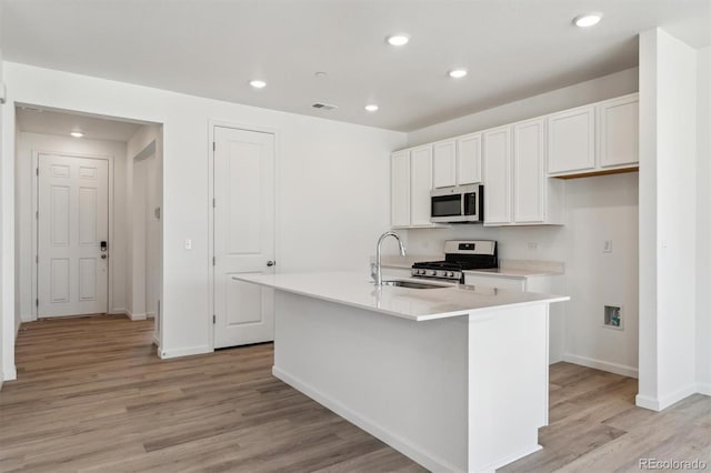 9672 Cathay St, Commerce City, CO 80022 - kitchen with stainless steel appliances, a kitchen island with sink, a sink, visible vents, and light wood-style floors