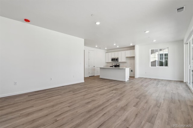 9672 Cathay St, Commerce City, CO 80022 - unfurnished living room featuring baseboards, light wood-style flooring, visible vents, and recessed lighting