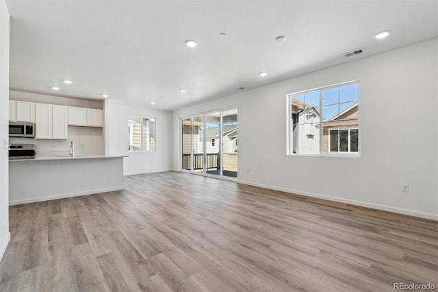 9672 Cathay St, Commerce City, CO 80022 - unfurnished living room featuring light wood-type flooring, baseboards, visible vents, and recessed lighting