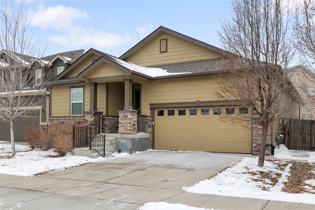 view of front of property featuring stone siding, an attached garage, and driveway