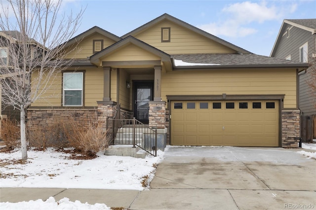 craftsman house with driveway, stone siding, an attached garage, and roof with shingles