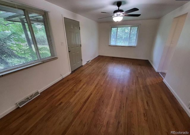 empty room with visible vents, ceiling fan, baseboards, and wood finished floors