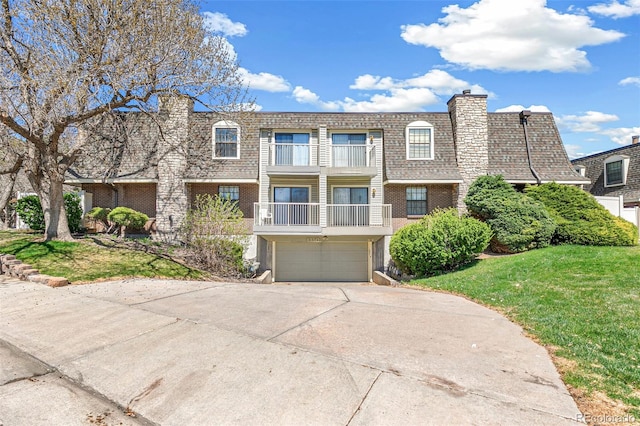 view of front of property with an attached garage, concrete driveway, brick siding, and a front lawn