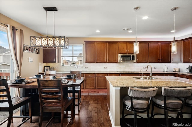 kitchen featuring an island with sink, sink, a breakfast bar area, and decorative light fixtures