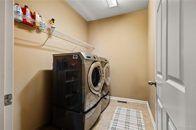 clothes washing area featuring light tile patterned floors and washer and dryer