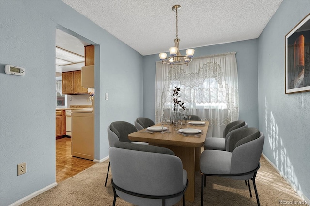 carpeted dining room with a chandelier and a textured ceiling