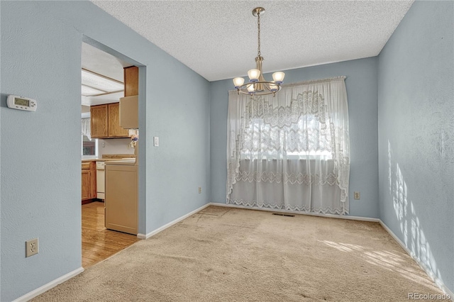 unfurnished room with light carpet, a notable chandelier, and a textured ceiling