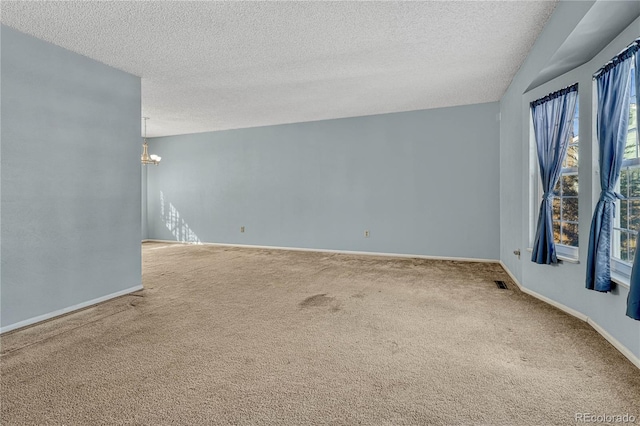 spare room with carpet floors, a chandelier, and a textured ceiling