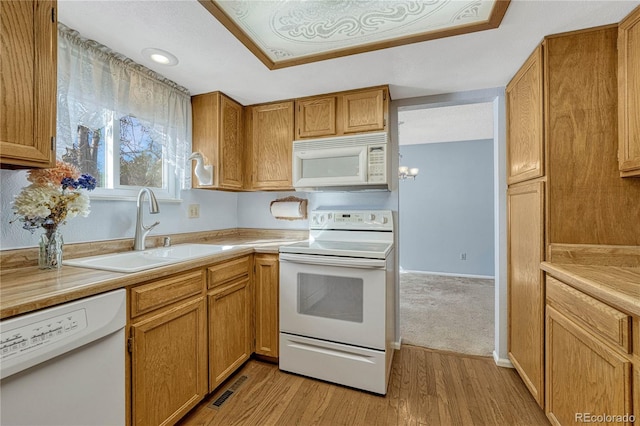 kitchen with sink, white appliances, and light hardwood / wood-style flooring