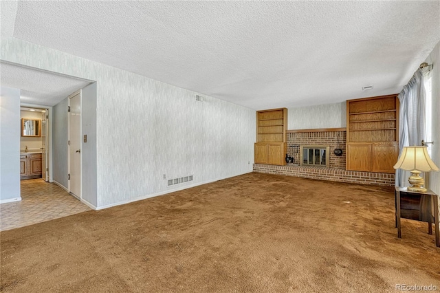 unfurnished living room with a fireplace, carpet floors, built in features, and a textured ceiling