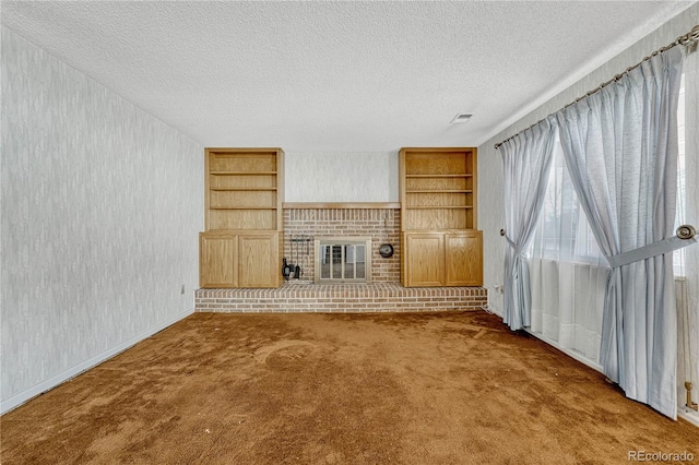 unfurnished living room with a fireplace, built in features, a textured ceiling, and carpet flooring