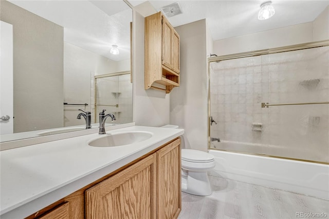 full bathroom featuring enclosed tub / shower combo, vanity, toilet, and hardwood / wood-style floors