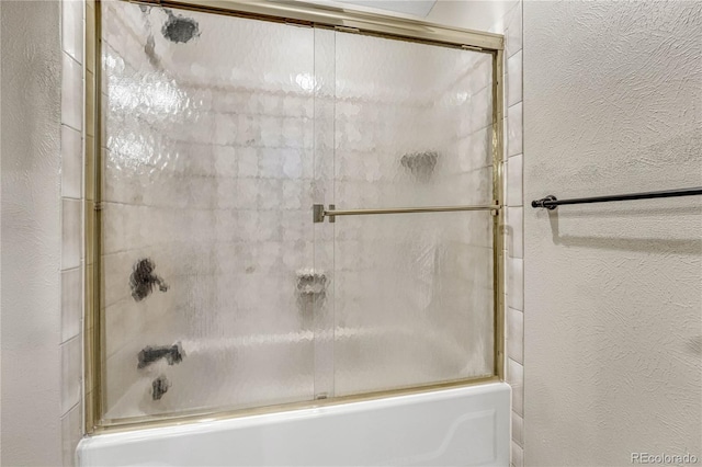 bathroom with bath / shower combo with glass door