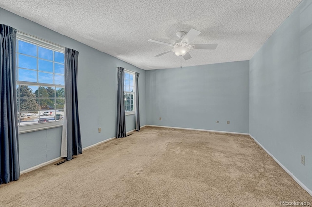 empty room featuring a textured ceiling, light colored carpet, and ceiling fan